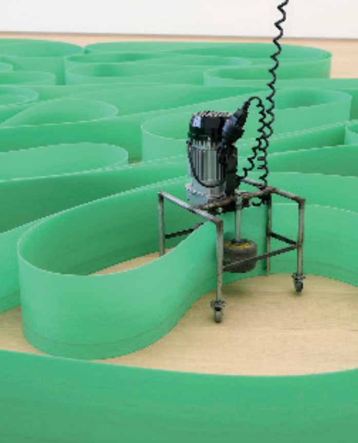 The machine at work with the green ribbon. The ribbon is formed in repeating loops.